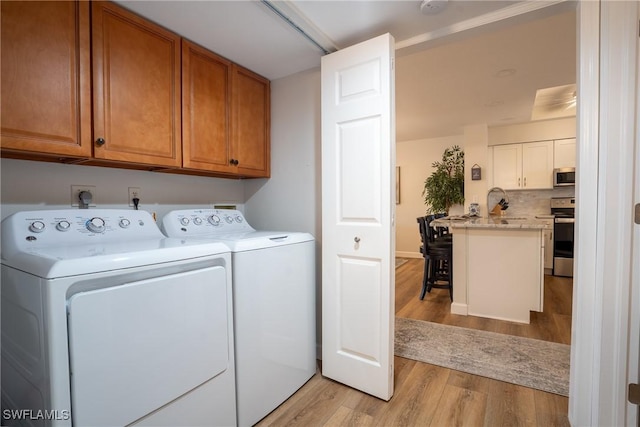 laundry room with washer and clothes dryer, light wood-type flooring, and cabinet space