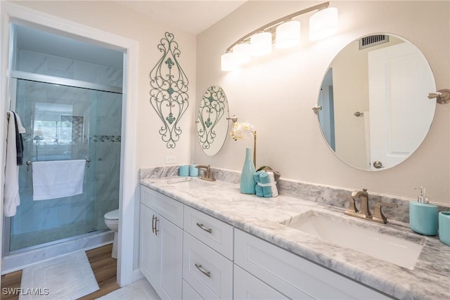 bathroom with toilet, a shower stall, visible vents, and a sink