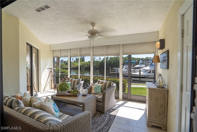 sunroom / solarium with a ceiling fan, a water view, and visible vents