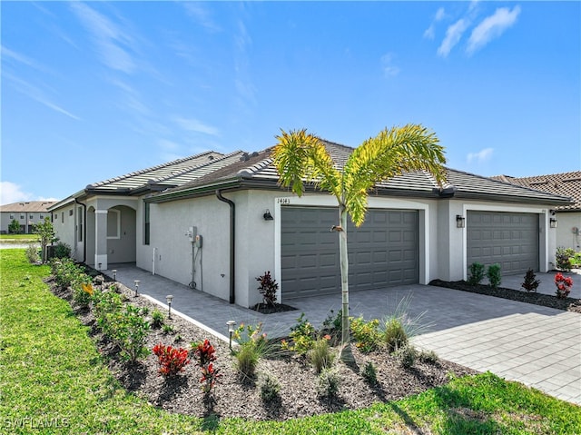 view of side of home with a tiled roof, a garage, decorative driveway, and stucco siding