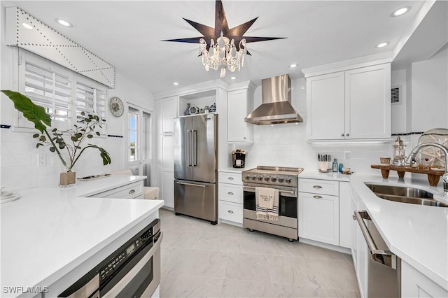 kitchen with high end appliances, white cabinetry, sink, and wall chimney exhaust hood