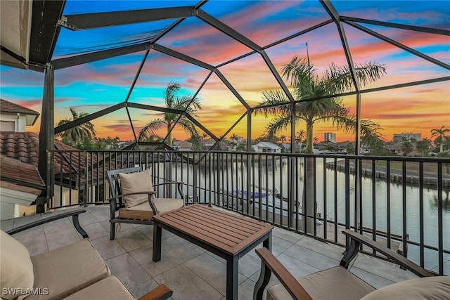 patio terrace at dusk featuring a water view and a balcony