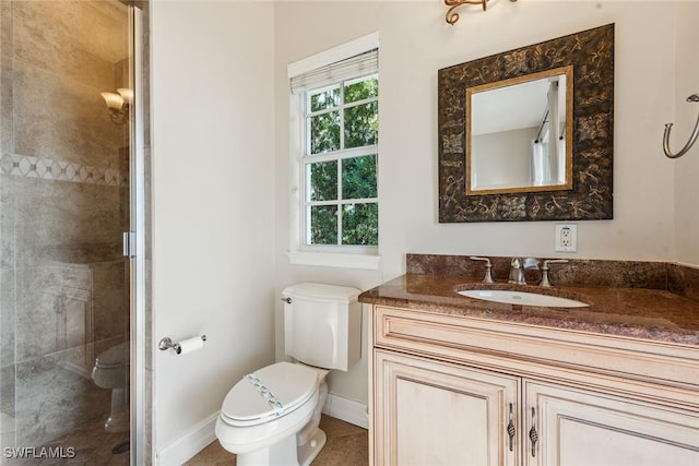 bathroom with toilet, vanity, and tiled shower