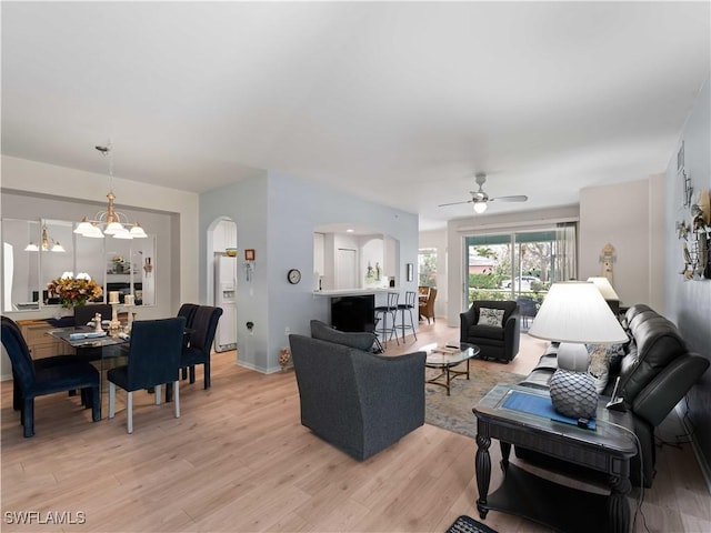 living room with ceiling fan with notable chandelier and light hardwood / wood-style floors