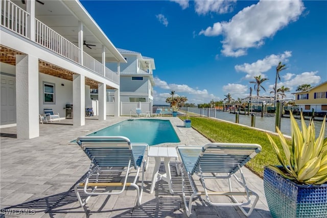 view of swimming pool with a water view, ceiling fan, and a patio area