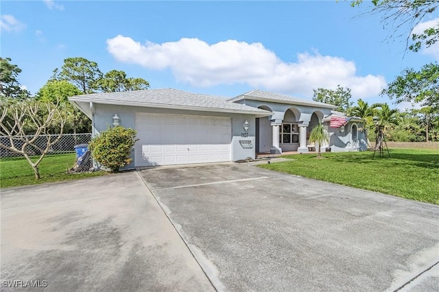 view of front of property featuring a garage, driveway, fence, a front lawn, and stucco siding