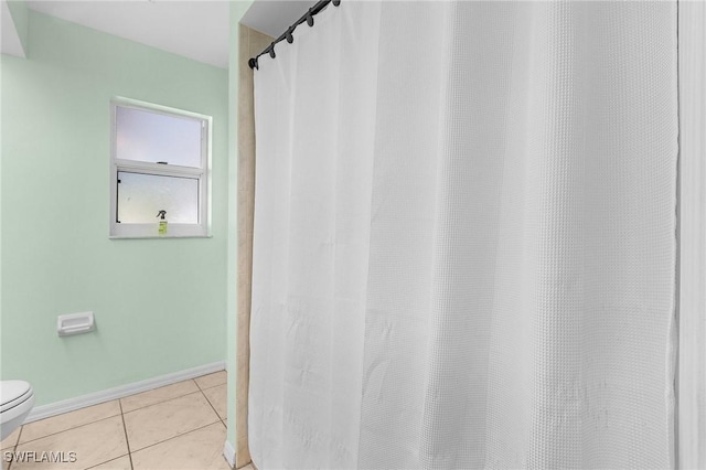 bathroom with baseboards, toilet, and tile patterned floors