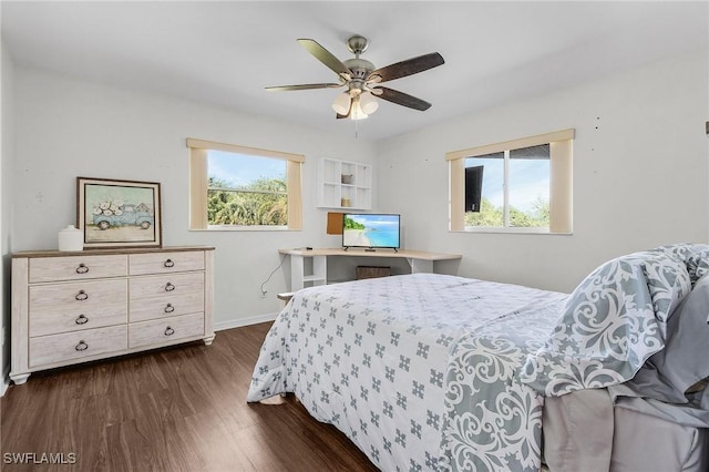 bedroom featuring multiple windows, dark wood finished floors, a ceiling fan, and baseboards