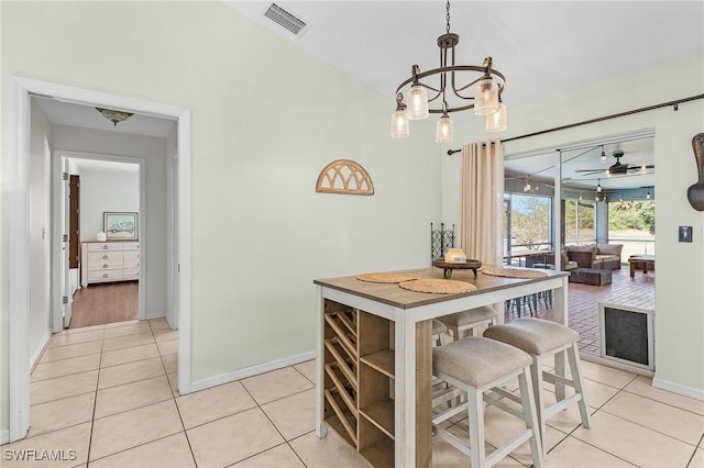 kitchen with light tile patterned floors, baseboards, visible vents, pendant lighting, and ceiling fan with notable chandelier