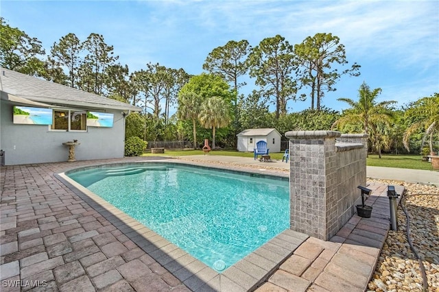 view of pool with a patio area, a storage shed, a fenced in pool, and an outdoor structure