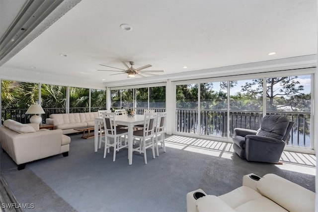 sunroom / solarium featuring a water view and ceiling fan