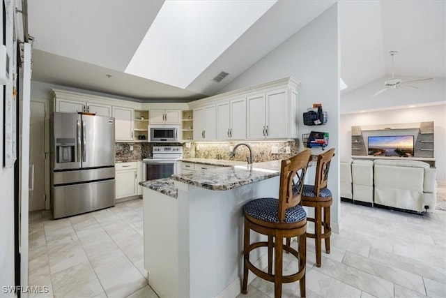 kitchen with visible vents, white cabinets, a peninsula, light stone countertops, and stainless steel appliances