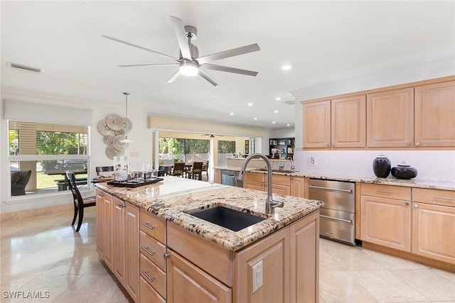 kitchen featuring light stone countertops, visible vents, a center island with sink, light brown cabinetry, and a sink