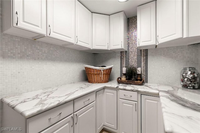 kitchen featuring decorative backsplash, white cabinets, and light stone countertops