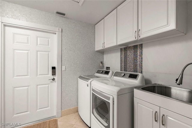 laundry room featuring light tile patterned floors, washing machine and clothes dryer, cabinet space, a sink, and tile walls