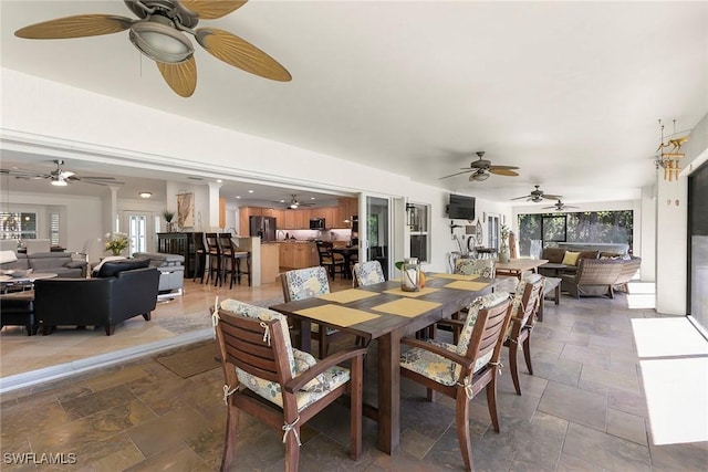 dining area with stone tile flooring, a healthy amount of sunlight, and ornate columns