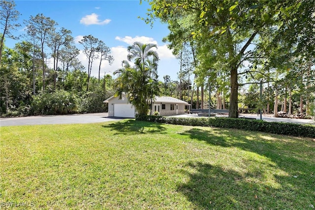 view of yard with aphalt driveway and a garage