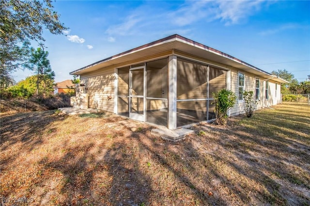 view of property exterior with a sunroom and a lawn