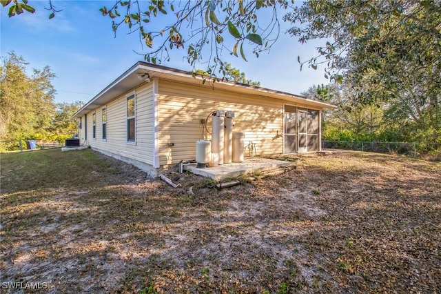 rear view of property with cooling unit, a sunroom, and a patio