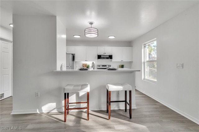 kitchen featuring white cabinetry, appliances with stainless steel finishes, a breakfast bar, and kitchen peninsula