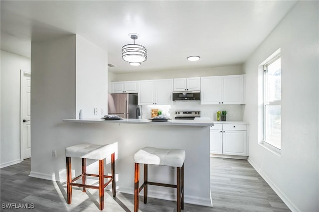 kitchen featuring white cabinetry, a breakfast bar area, kitchen peninsula, and appliances with stainless steel finishes