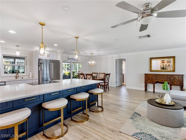 kitchen with ornamental molding, a kitchen breakfast bar, decorative light fixtures, black electric cooktop, and high end fridge