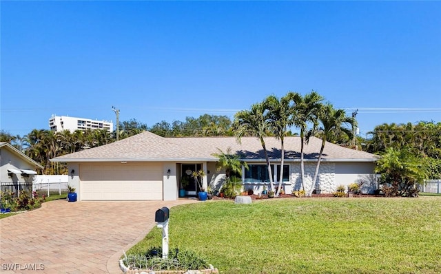 ranch-style house featuring an attached garage, fence, decorative driveway, a front yard, and stucco siding