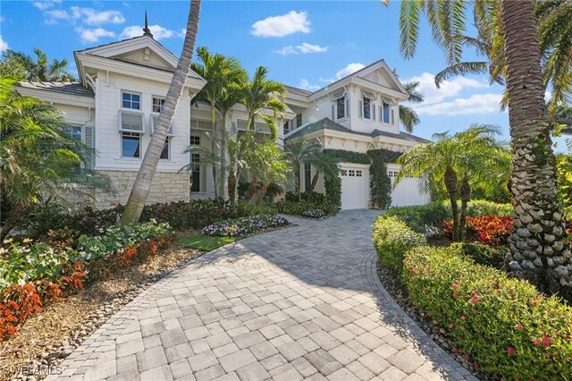 view of front facade with an attached garage, stone siding, and decorative driveway