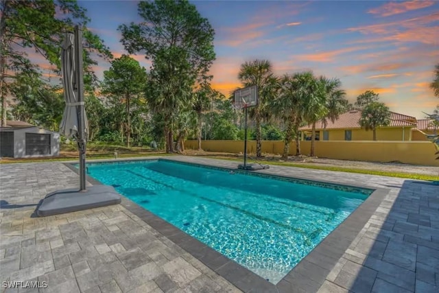 pool at dusk featuring a patio