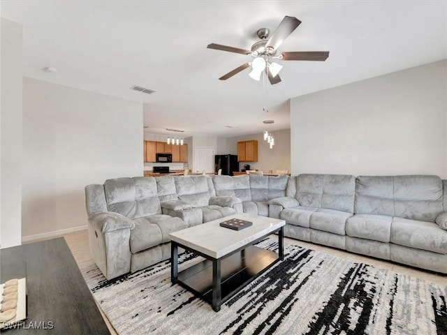 living room featuring ceiling fan with notable chandelier and light wood-type flooring