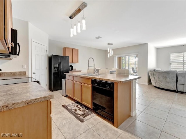 kitchen featuring sink, hanging light fixtures, light tile patterned floors, a kitchen island with sink, and black appliances