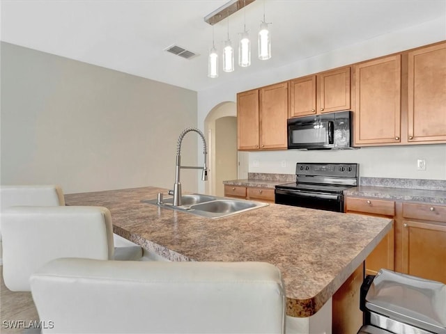 kitchen with a kitchen island with sink, sink, a kitchen breakfast bar, and black appliances