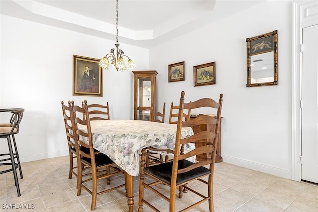 tiled dining room with an inviting chandelier and a tray ceiling