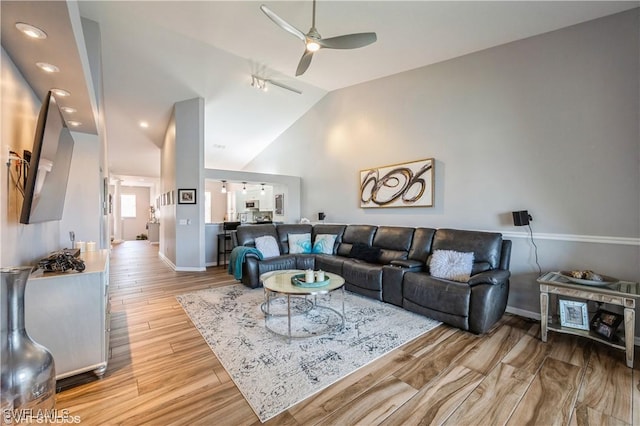 living room with light hardwood / wood-style floors, high vaulted ceiling, and ceiling fan