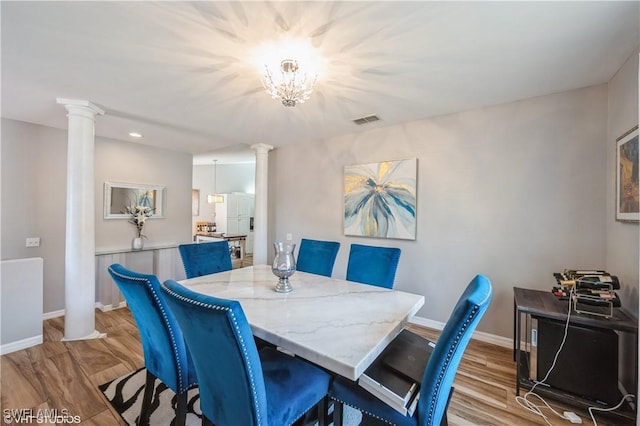 dining room with light hardwood / wood-style flooring and decorative columns