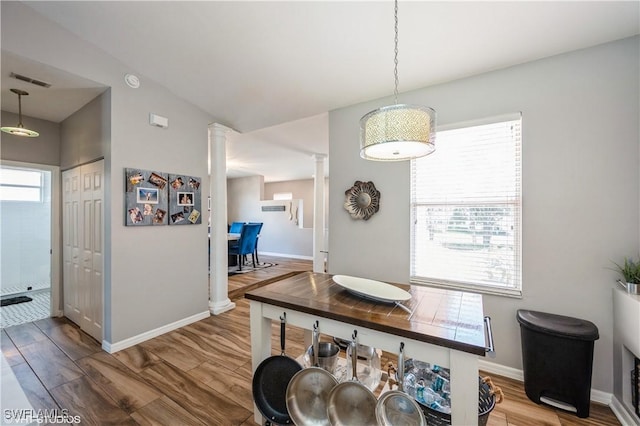 dining area with hardwood / wood-style flooring, plenty of natural light, decorative columns, and lofted ceiling