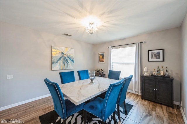 dining space with hardwood / wood-style floors and a notable chandelier