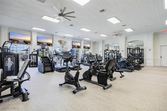 exercise room featuring crown molding, ceiling fan, light carpet, and ornate columns