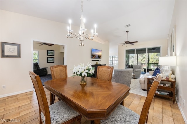 dining space with vaulted ceiling, a healthy amount of sunlight, ceiling fan with notable chandelier, and light hardwood / wood-style flooring