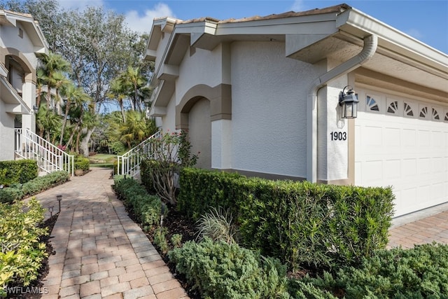 5644 Sandlewood Ct Unit 1903, Naples, FL 34110 - view of home's exterior with stucco siding, a garage, and stairway