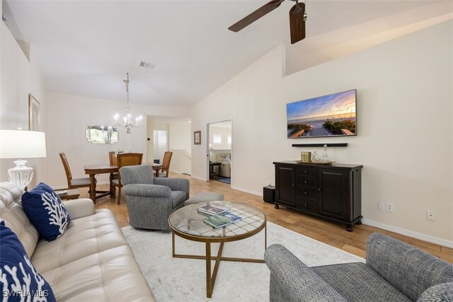 living room featuring high vaulted ceiling, ceiling fan with notable chandelier, and light hardwood / wood-style flooring