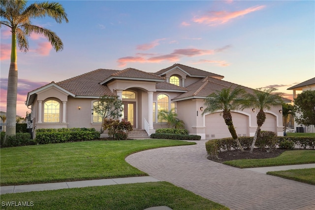 mediterranean / spanish-style house with a garage and a lawn