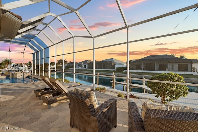 exterior space featuring a water view, a dock, glass enclosure, and a patio area