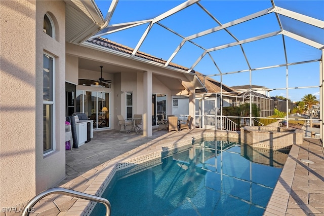 view of swimming pool with a patio, ceiling fan, and glass enclosure