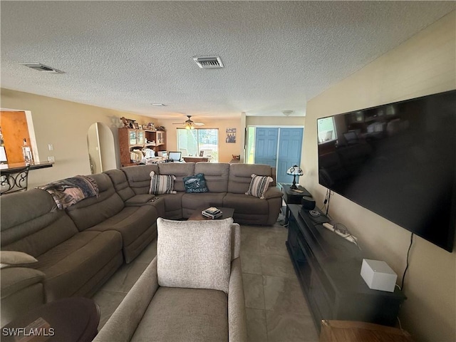 living area with arched walkways, visible vents, and a textured ceiling