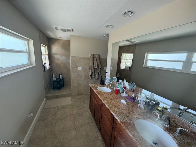 full bathroom featuring double vanity, a wealth of natural light, and a sink