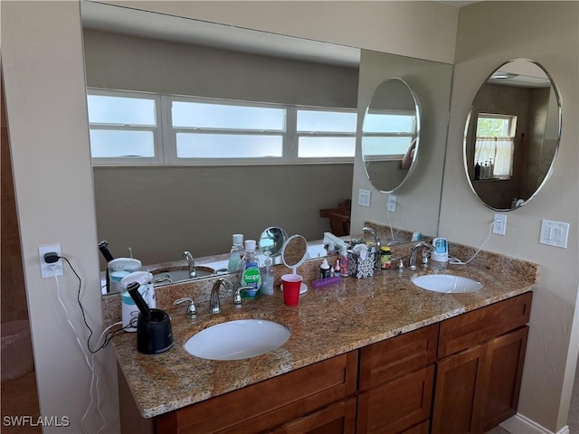 bathroom with double vanity, a sink, and a healthy amount of sunlight