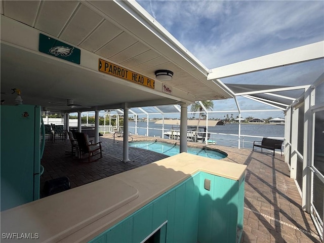 view of patio / terrace with a water view, a lanai, and an outdoor pool