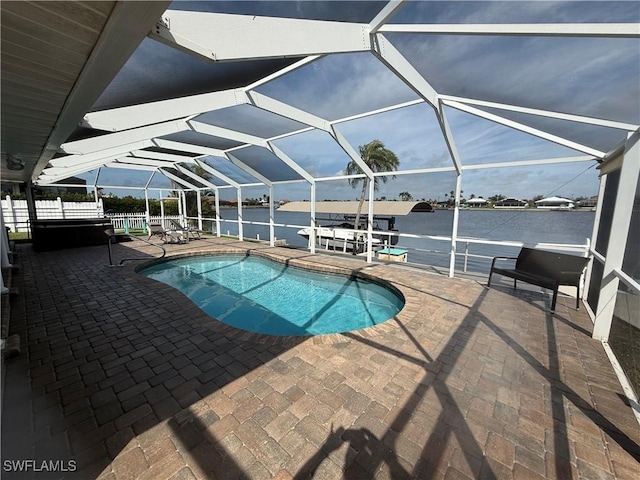 outdoor pool featuring a patio area, glass enclosure, a water view, and fence