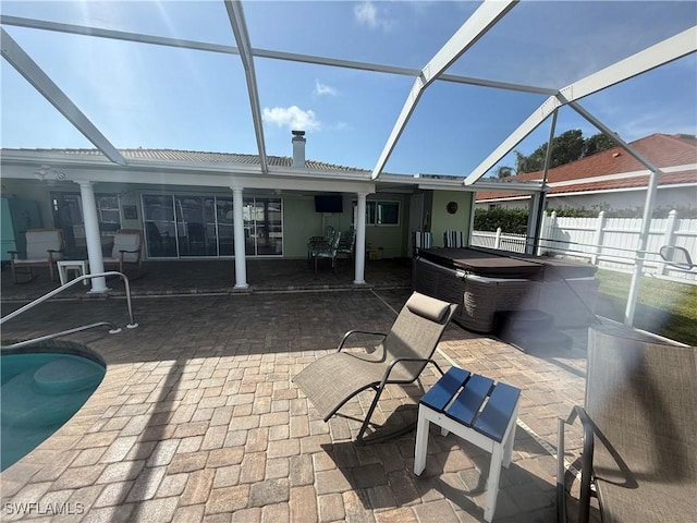 view of patio / terrace with a lanai, fence, a fenced in pool, and a hot tub